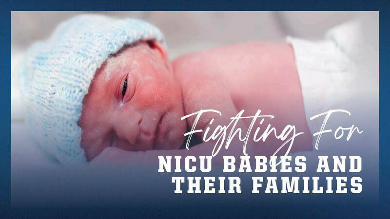 A newborn NICU baby laying on it's stomach wearing a knit cap.