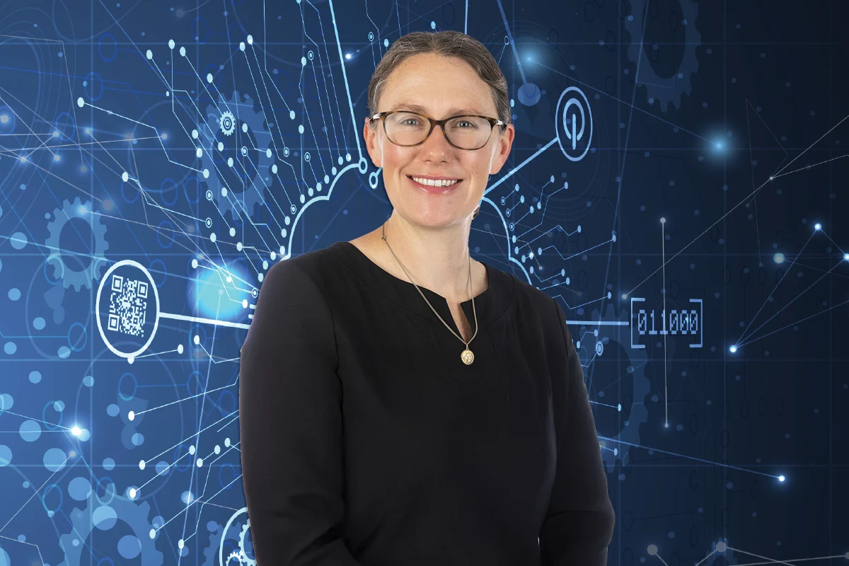 A smiling woman with glasses and brown hair pulled back stands in front of a dark blue background with abstract white digital lines and binary code.