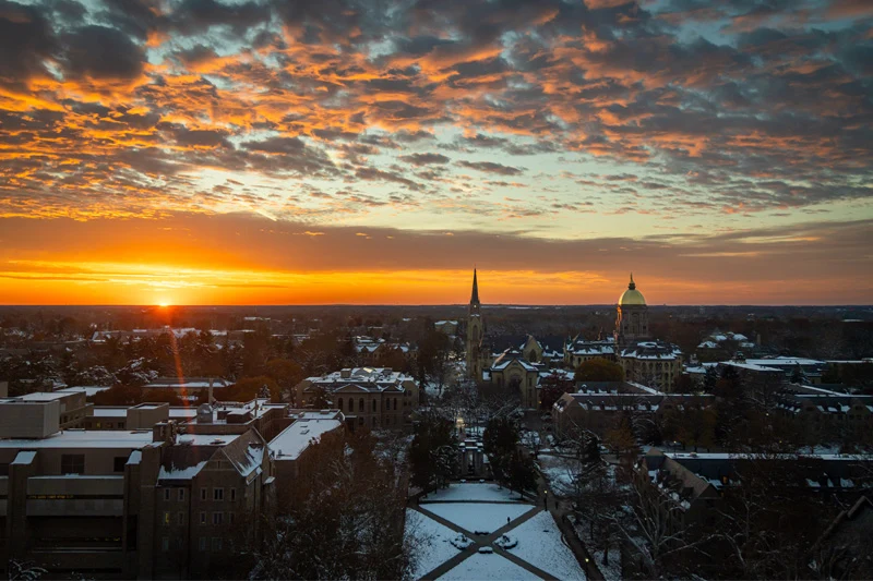 Aerial view of a red and organge sunset over the skyline of the Notre Dame campus