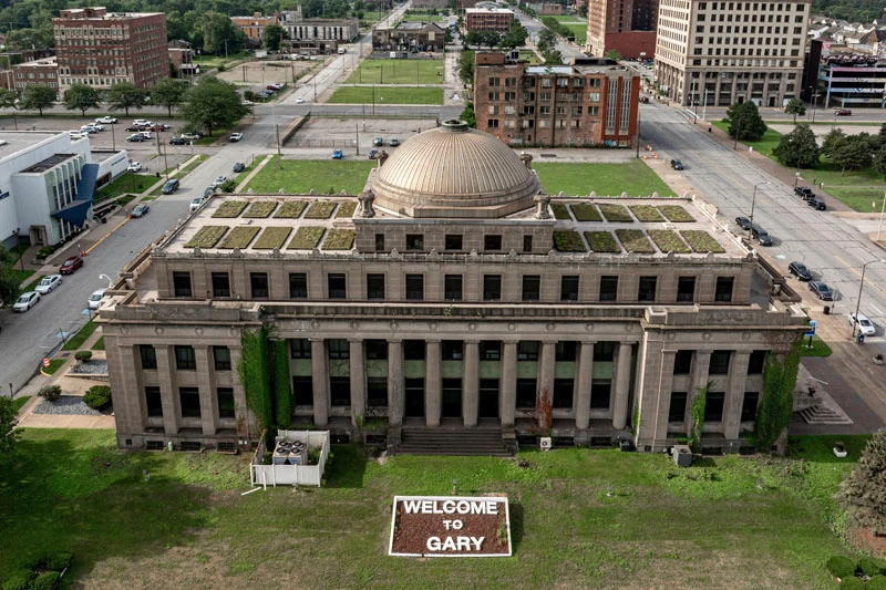 Aerial view of the classical, domed former Gary City Hall building with a 'Welcome to Gary' sign on the front lawn.