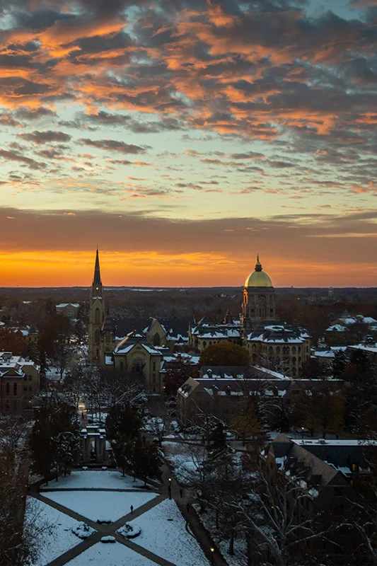 The sun sets over the Notre Dame campus skyline.