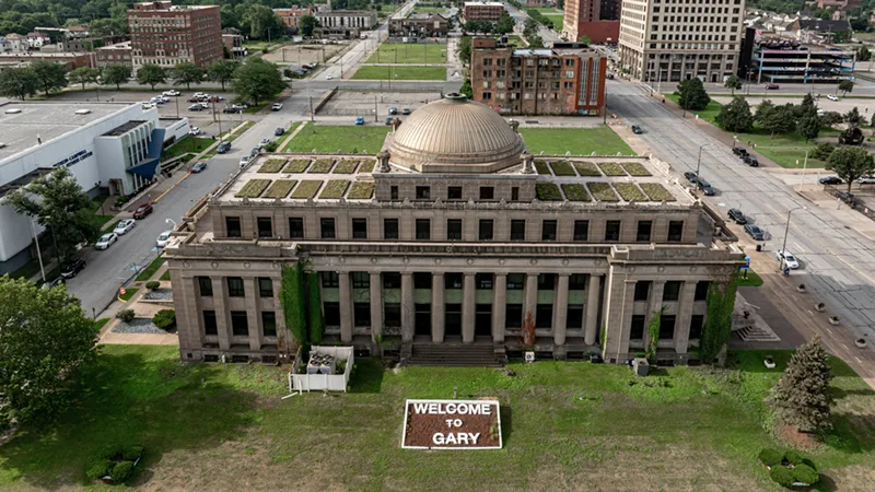Aerial view of the classical, domed former Gary City Hall building with a 'Welcome to Gary' sign on the front lawn.