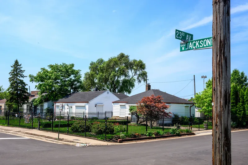 The Jackson Five childhood home, a small white house with a black fence, on a corner with street signs reading 23rd Ave and W Jackson St.