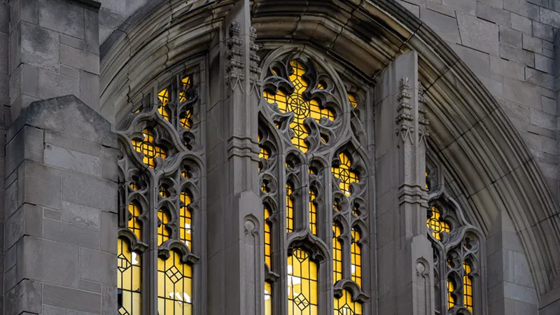 Close-up of the Gothic-style stone tracery and bright yellow windows of a community church.