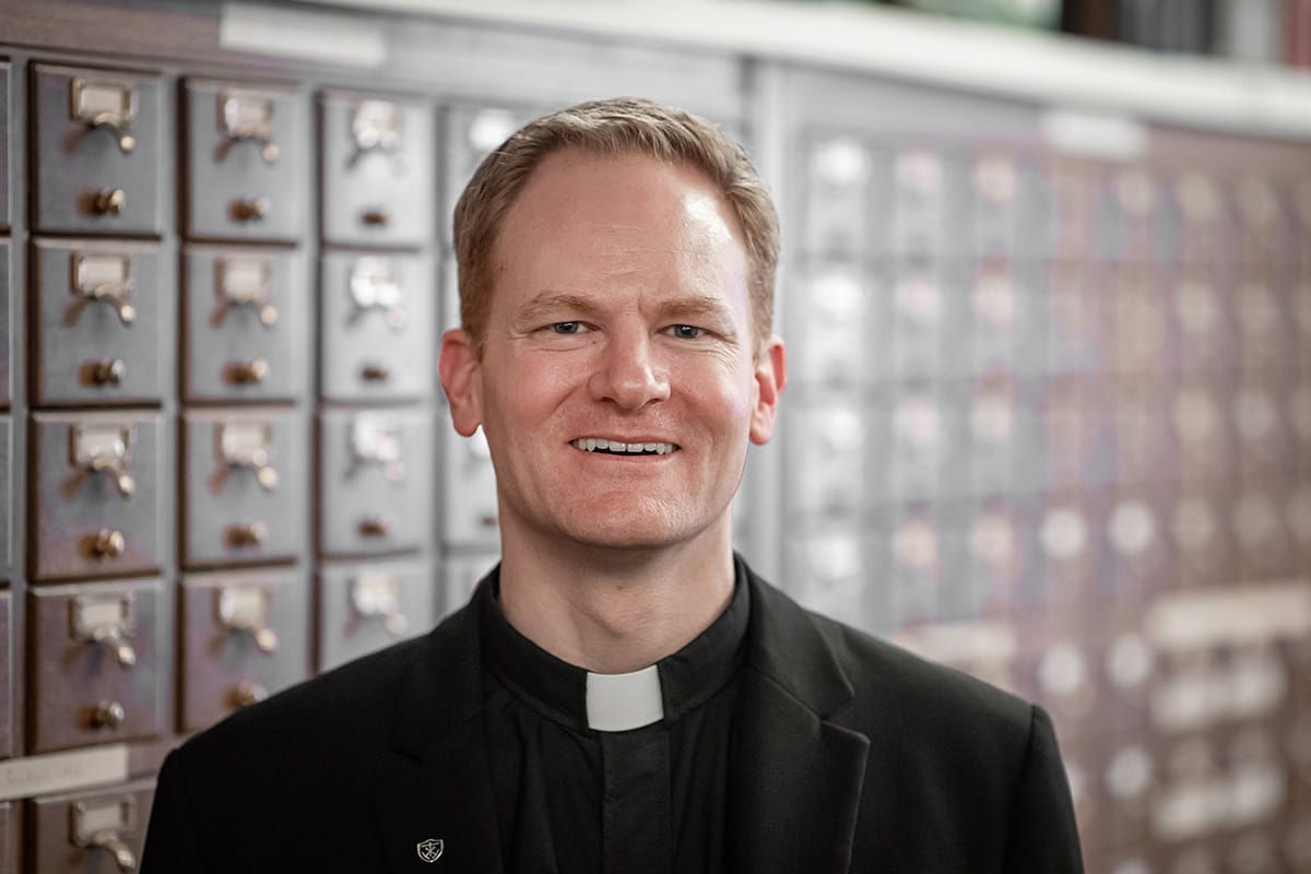 A photo of a white man with red hair in priest&rsquo;s robe.